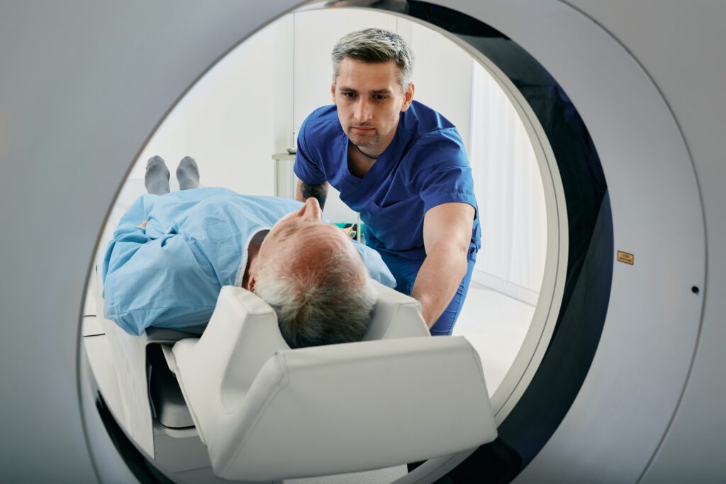 Senior man going into CT scanner. CT scan technologist overlooking patient in Computed Tomography scanner during preparation for procedure